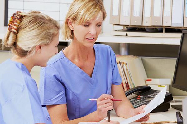 two nurses reviewing paperwork at a desk